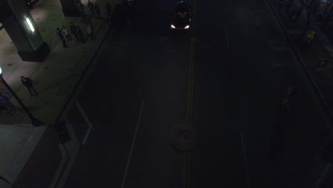 Aerial---Descending-drone-shot-on-dark-street-with-dim-street-lights-at-night