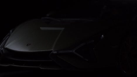 Frontaufnahme-Eines-Lamborghini-Sians,-Der-Durch-Licht-Aus-Der-Dunkelheit-Hervorgeholt-Wird