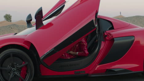 Red-McLaren-car-driving-with-scissor-doors-open,-slow-motion,-Dubai-Desert