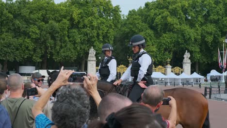 Crowd-Of-People-Taking-Photos-Of-Policewoman-On-Horses-Outside-Buckingham-Palace-In-London,-England