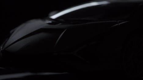 Light-revealing-shot-of-the-front-of-a-black-Lamborghini-sports-car