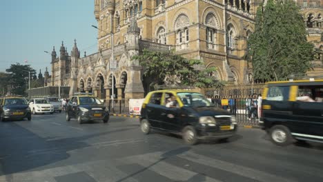 Daytime-traffic-across-streets-of-Chhatrapati-Shivaji-Maharaj-Terminus-station-with-CSMT-building-at-background,-Mumbai