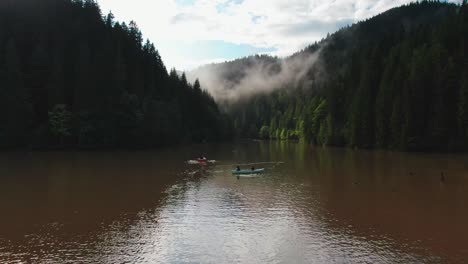 Mehrere-Kajaks-Schwimmen-Einen-Fluss-Hinunter-In-Einem-Kiefernwald-Mit-Nebligen-Baumkronen