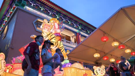 A-family-poses-for-a-photo-in-front-of-a-tiger-theme-lantern-and-part-of-a-lantern-show,-which-symbolizes-prosperity-and-good-fortune,-at-the-Wong-Tai-Sin-temple-during-the-Mid-Autumn-Festival