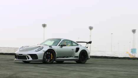 Slow-motion-drive-by-shot-of-a-silver-Porsche-GT3-RS-on-a-drift-track