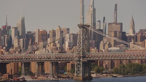 Wide-zoom-shot-showing-train-crossing-Manhattan-bridge-in-front-of-skyline-in-New-York