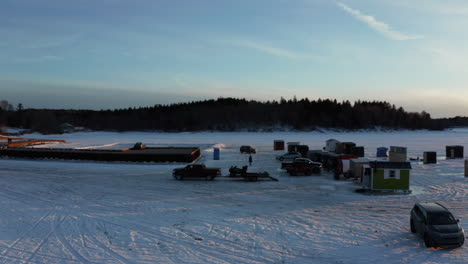 Malerische-Luftaufnahme-Von-Eisfischerhütten-Auf-Einem-Zugefrorenen-See-Bei-Sonnenuntergang