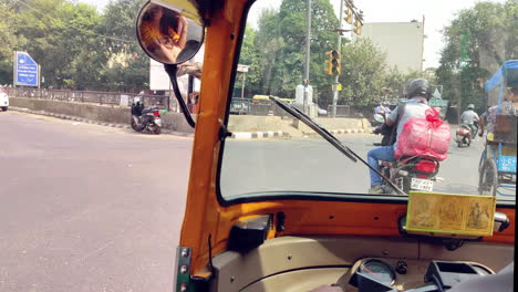 Montar-El-Auto-Rickshaw-En-La-Concurrida-Calle-De-CP-Con-El-Reflejo-De-Una-Dama-En-El-Espejo-Lateral,-Nueva-Delhi,-India