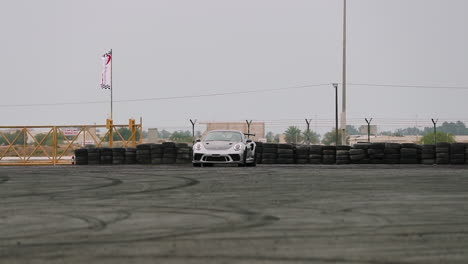 Slow-motion-tracking-shot-of-a-silver-Porsche-GT3-RS-drifting-around-a-race-track