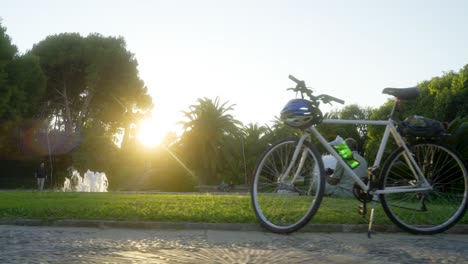 Radfahrer-Sitzt-Im-Gras-Neben-Seinem-Fahrrad-Am-Großen-Brunnen-Am-Aussichtspunkt-Montjuic-In-Barcelona,-Spanien,-Während-Des-Sonnenuntergangs-An-Einem-Warmen-Nachmittag-Im-Herbst