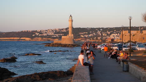 Slow-motion-tourists-sightseeing-on-Chania-waterfront-under-scenic-Greek-island-lighthouse-promenade