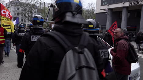 Una-Unidad-De-Policías-Antidisturbios-Vestidos-De-Civil,-Con-Cascos-Y-Chalecos-Antibalas,-Camina-Entre-Una-Multitud-De-Manifestantes.