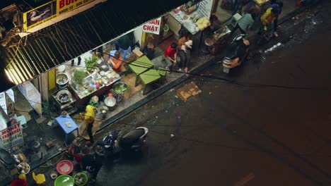 Man-making-Vietnamese-food-with-vegetables-at-a-Vietnam-Street-food-stall-at-night-in-Hanoi,-looking-out-from-the-city-balcony