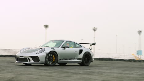 Grey-sports-car-cruising-past-on-a-track-in-slow-motion-with-slight-camera-wobble