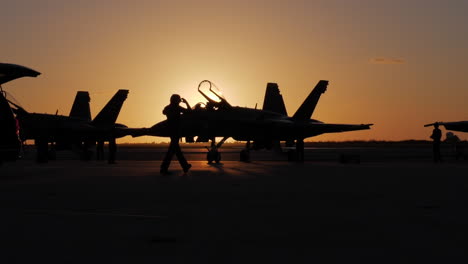 Wider-silhouette-shot-of-Naval-Officer-walking-in-front-of-a-Blue-Angel-on-the-tarmac-as-the-jets-are-prepped-for-an-airshow-routine-early-morning-sunrise-in-Key-West