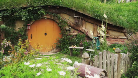 Uriges-Hobbit-Höhle-Im-Hobbiton-Filmset-Mit-Schönen-Weißen-Blumen,-Die-Die-Vorderseite-Des-Hauses-Schmücken