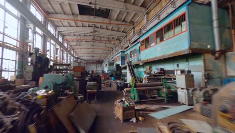 Aerial-view-flying-low,-over-machines-inside-an-old-car-manufactory-hall---FPV,-drone-shot