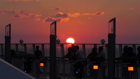 Silhouette-cruise-passengers-walking-along-the-deck-in-slow-motion-during-a-gorgeous-pink-and-purple-sunset
