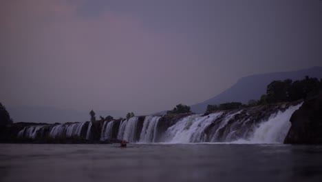 man-swimming-in-laotian-waterfalls-at-dusk
