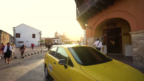 Culturally-rich-streets-of-Cartagena-during-bright-sunset,-yellow-taxies,-slow-motion