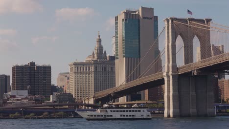 Static-wide-shot-of-cruising-boat-on-East-River-with-Verizon-Building-in-background---New-York-City-at-sunset-time