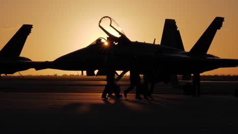 Silhouette-Von-Marineoffizieren,-Die-Vor-Einem-Blauen-Engel-Auf-Dem-Rollfeld-Laufen,-Während-Die-Jets-Für-Eine-Flugshow-Am-Frühen-Morgen-Des-Sonnenaufgangs-In-Key-West-Vorbereitet-Werden