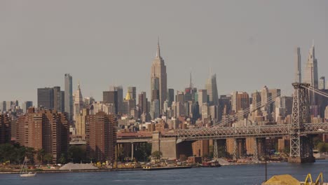 Panorama-Weitwinkelaufnahme-Des-East-River,-Der-Manhattan-Bridge-Und-Der-Skyline-Mit-Dem-Empire-State-Building-Im-Hintergrund-Bei-Sonnenuntergang