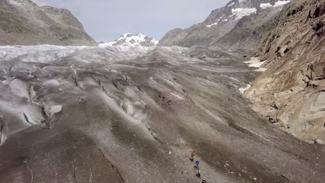 Luftaufnahme-Von-Zwei-Seilschaften,-Die-Einen-Gletscher-Hinabsteigen,-Mit-Einem-Berg-Im-Hintergrund