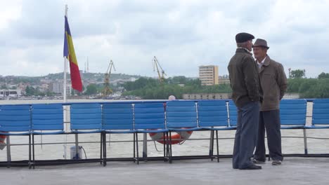 two-old-romanian-men-talking-on-the-deck-of-a-moving-danube-passenger-ferry