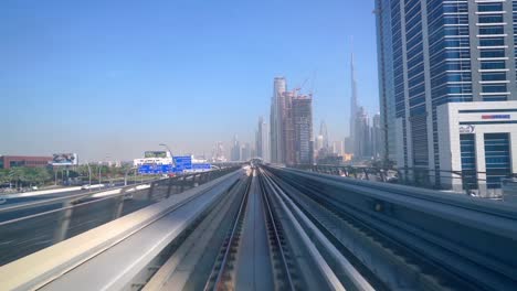 Vista-Del-Burj-Khalifa-Y-Del-Horizonte-Del-Centro-Desde-El-Tren-Del-Metro-De-Dubai-En-Movimiento-En-Un-Día-Soleado-En-Dubai,-Emiratos-Árabes-Unidos