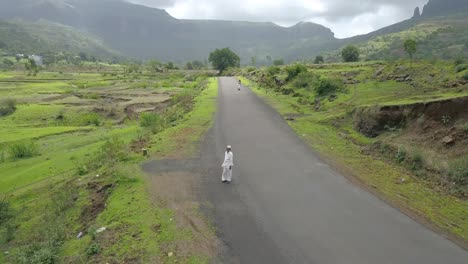 Traditional-Indian-man-on-a-countryside-road,-Aerial-Take-off