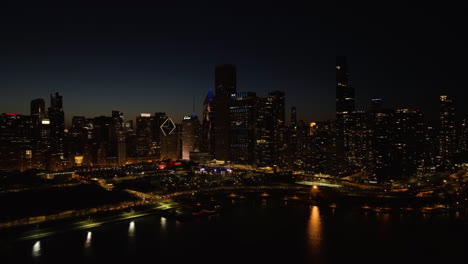 Traffic-moving-in-front-of-the-Illuminated-New-Eastside-skyline,-night-in-Chicago,-USA---motion-time-lapse