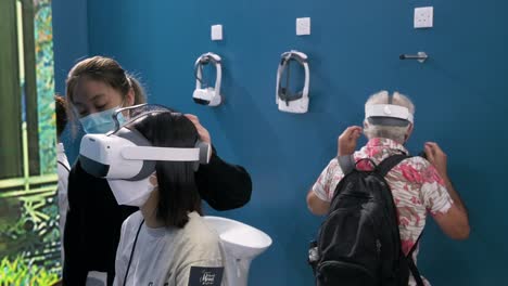 Visitors-try-and-wear-virtual-reality-headsets-to-experience-an-immersive-adventure-simulator