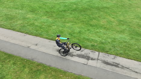 Freestyle-Cyclist-Riding-His-Bicycle-on-Track-in-Park,-Drone-Aerial-View