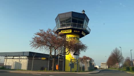 Toma-Pov-De-La-Torre-De-Control-De-Tráfico-Del-Aeropuerto-Amarillo-Negro-En-Dortmund-Con-Publicidad-Del-Borussia-Dortmund