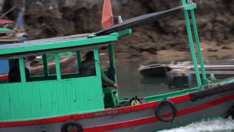 tracking-shot-of-a-vietnamese-man-driving-on-a-vietnamese-wooden-boat-at-halong-bay