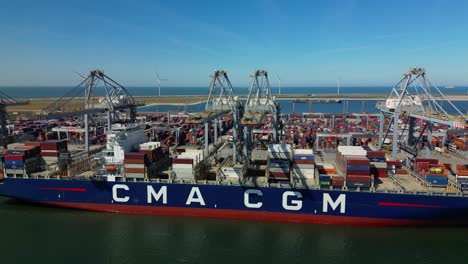 Drone-trucking-shot-of-a-large-CMA-CGM-vessel-docked-at-RWG-terminal-in-the-port-of-Rotterdam-on-a-sunny-day