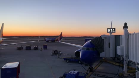 Airport-establishing-shot-as-airplane-taxis-on-runway-at-sunrise-with-airplanes-in-foreground