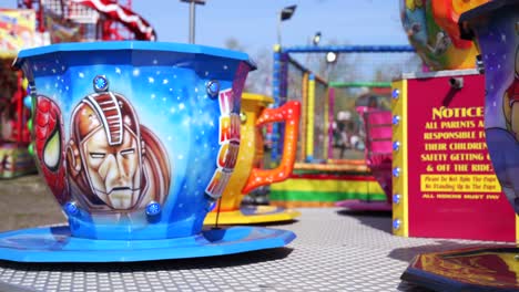 Colourful-blue-amusement-park-teacup-fairground-ride-spinning-in-slow-motion-on-carousel-attraction
