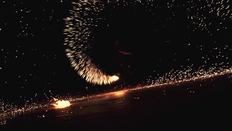 Performer-spinning-burning-sparking-torch-on-beach-festival-at-night