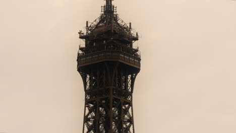 Top-Summit-of-Eiffel-Tower-in-City-of-Paris-on-Cloudy-Day,-Zoomed-View