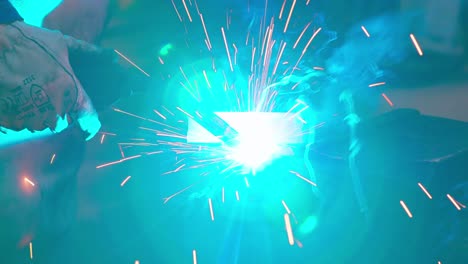 Welder-welding-metal-steel-iron,-bright-blue-yellow-sparks-fly,-close-up