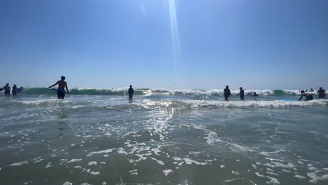 Ocean-waves-crash-into-the-camera-as-tourists-swim