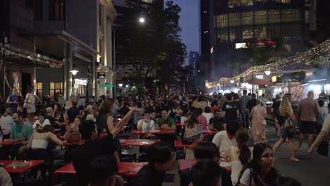 Crowds-of-locals-and-tourists-chit-chatting-while-waiting-for-their-satay-in-the-middle-of-a-bustling-food-market-at-Lau-Pa-Sat,-Singapore