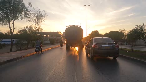 Karachi,-Pakistan:-Car-ride-on-a-busy-evening-in-Karachi-city,-Pakistan-with-sun-setting-in-the-background