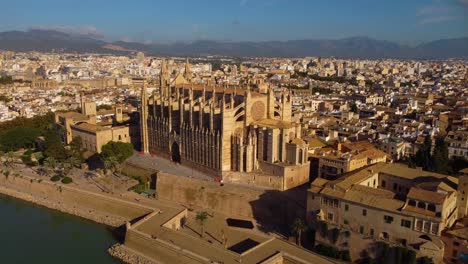 4K-pedestal-shot-of-the-Catedral-Basílica-de-Santa-María-de-Mallorca,-finishing-with-a-deep-tilt-to-reveal-the-building-from-above