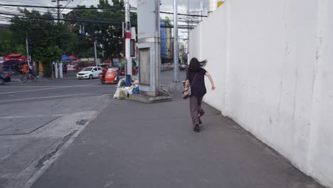 Woman-runs-along-sidewalk-looking-back-in-fear-races-around-corner-bend-by-road