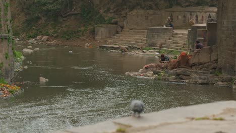 Nepalíes-Sentados-Junto-A-Un-Río,-Que-Fluye-A-Través-De-Las-Ruinas-De-Las-Escaleras-Del-Antiguo-Templo,-En-Katmandú,-Nepal