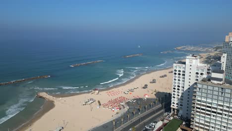 Die-Meeresstrandlandschaft-In-Tel-Aviv,-Israel,-Zeigt-Die-Küste-Im-Schatten-Unter-Sonnenschirmen,-Sanfte-Wellen,-Die-An-Die-Küste-Schlagen