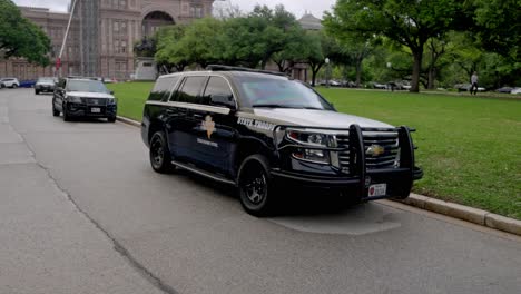 Texas-state-capitol-building-in-Austin,-Texas-with-gimbal-video-walking-along-road-with-state-trooper-cars